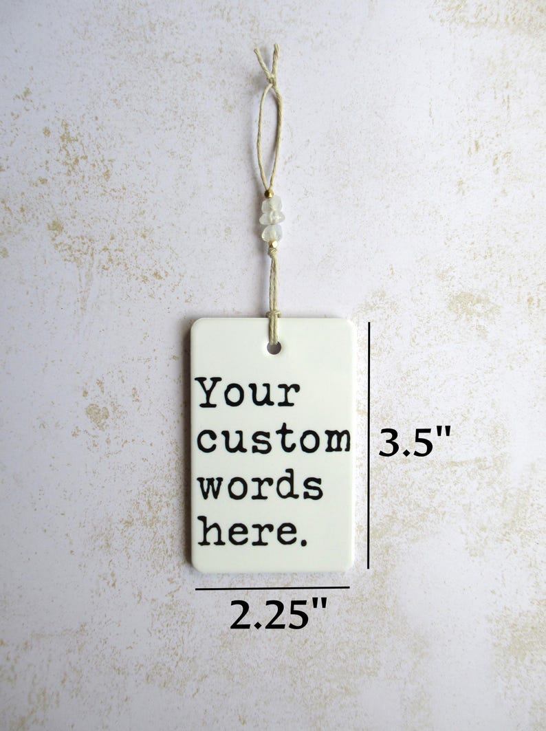 May include: A rectangular white ornament with the text "Your custom words here." It measures 3.5 inches tall and 2.25 inches wide. The ornament hangs from a string with beads.
