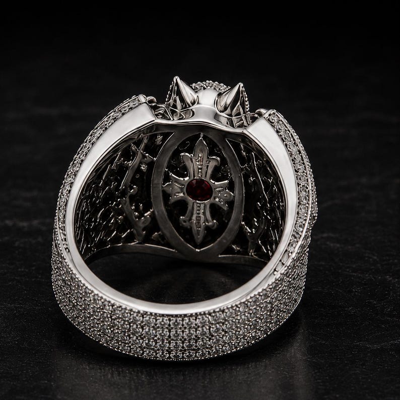 Side angle closeup of gothic bat wing ring with large red ruby center stone, black gemstone accents, and detailed silver pave setting. Luxury fantasy statement ring inspired by vampire and dragon themes, gothic jewelry for women and men, Halloween ring, dark aesthetic accessory, alternative fashion jewelry, biker ring, cosplay accessory, unique gothic engagement ring, handmade fantasy cocktail ring with bold dramatic design.
