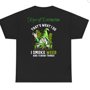 May include: Black t-shirt with a graphic of a gnome smoking a joint, surrounded by cannabis plants. Text reads "Keys of Distinction, That's What I Do, I Smoke Weed and I Know Things."
