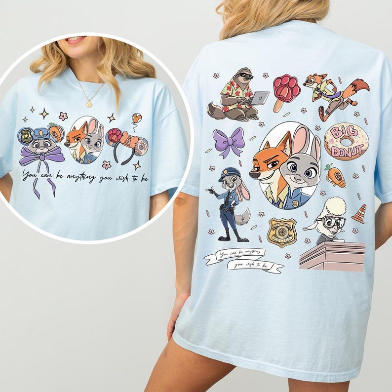 May include: Light blue t-shirt featuring cartoon characters and the text "You can be anything you wish to be." The front of the shirt has character faces and bows. The back has more characters and a donut.
