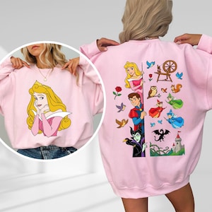 Puede incluir: Sudadera rosa claro con una ilustraci&oacute;n de dibujos animados de una princesa en la parte delantera. La parte posterior de la sudadera tiene un gr&aacute;fico m&aacute;s grande con personajes y elementos adicionales de la misma pel&iacute;cula animada. El dise&ntilde;o incluye un castillo, un drag&oacute;n y otros personajes.