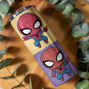 May include: A stainless steel tumbler featuring a cartoon Spider-Man design. The tumbler has a yellow and purple background with two images of Spider-Man. The character is depicted in his classic red and blue suit with a web-like pattern on his mask.