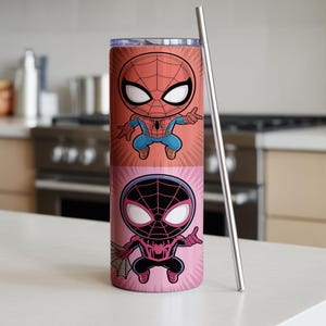 May include: A tall, cylindrical tumbler featuring two cartoon Spider-Man characters. The top half displays a red and blue Spider-Man, while the bottom half shows a black and pink Spider-Man. A silver straw is placed next to the tumbler.