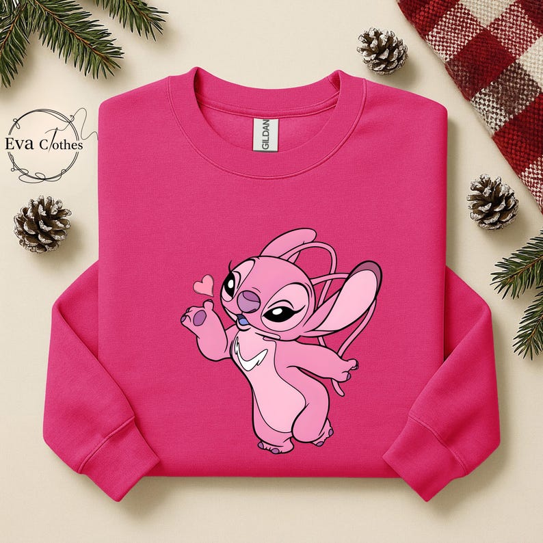 Puede incluir: Una sudadera rosa brillante con un personaje de dibujos animados en tonos rosas, sosteniendo un peque&ntilde;o coraz&oacute;n rosa. El personaje tiene ojos grandes y orejas largas. La sudadera tiene cuello redondo y mangas largas.