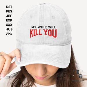 May include: A white baseball cap featuring the embroidered phrase "MY WIFE WILL KILL YOU" in red. The cap has a curved peak and an adjustable strap, a classic design.