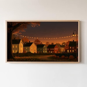 May include: A framed horizontal wall art print depicting a nighttime autumn village scene with several houses, glowing string lights, a large tree on the left, and orange pumpkins resting on the ground under a dark, warm-toned evening sky.
