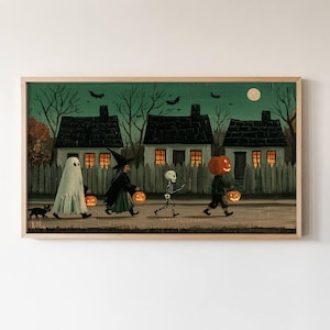 May include: A rectangular framed wall art print depicting a Halloween scene with four figures in costumes—a ghost, a witch, a skeleton, and a pumpkin-headed person—walking past three houses at night under a full moon with a black cat nearby.