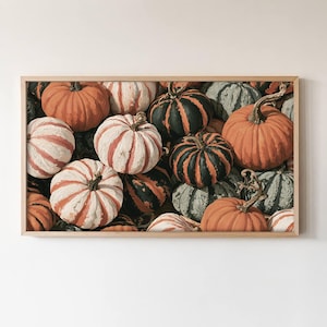 May include: A rectangular wall art print featuring a dense arrangement of pumpkins in various colors including orange, white, and dark green. The pumpkins have distinct ribbed textures and stems, displayed within a light-colored wooden frame.