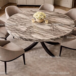 Peut inclure: Une table à manger ronde en marbre avec un motif gris et blanc, entourée de six chaises rembourrées. La table a un socle sombre et est ornée d'un vase de fleurs. Les chaises ont des pieds foncés.