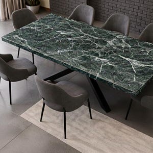 May include: A rectangular dining table with a green marble top and a black metal base. Six gray upholstered chairs with black legs surround the table, creating a modern dining set. A neutral rug is placed beneath the table.