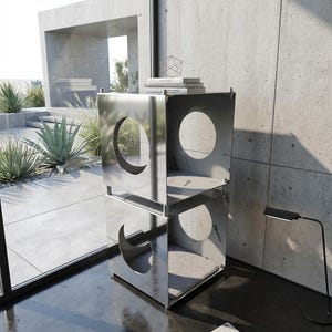 Può includere: Un moderno mobile per gatti in metallo lucido, con un design a cubi impilati. Ogni cubo presenta un'apertura circolare e un morbido cuscino interno grigio. L'unità è posizionata vicino a una finestra, con un'estetica minimalista.