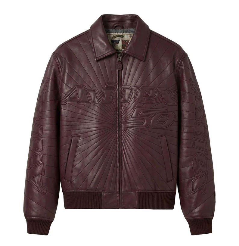 May include: A burgundy leather jacket with a zip-up front, collar, and ribbed cuffs and hem. The jacket features the embossed text "Avirex 50" on the chest and sleeves, with a sunburst design radiating from the center.