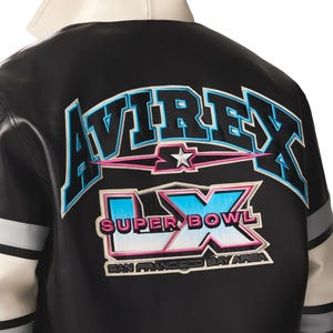 Puede incluir: Chaqueta de cuero negra con detalles en blanco y gris. La parte trasera presenta la palabra "AVIREX" en letras azules y rosas, junto con "SUPER BOWL LX" y "SAN FRANCISCO BAY AREA".