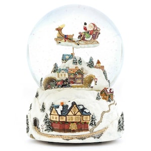 Peut inclure: Un globe de neige sur le thème de Noël avec le Père Noël dans un traîneau tiré par un renne, au-dessus d'un village. La base est un paysage enneigé avec des maisons, des arbres et un train. Le globe est transparent avec des paillettes flottantes.