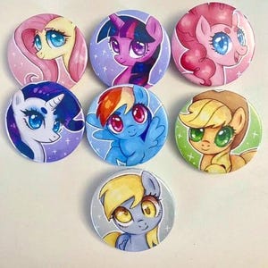 Könnte beinhalten: Ein Set aus sieben runden Ansteckbuttons mit farbenfrohen Illustrationen von Zeichentrickponys. Jeder Button zeigt eine andere Figur mit individueller Mähnenfarbe, Augenfarbe und Mimik vor verschiedenen pastellfarbenen Hintergründen mit Sternen.