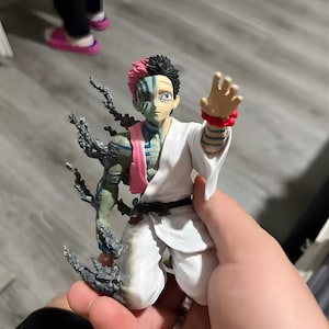 Könnte beinhalten: Detaillierte Figur eines Charakters mit geteiltem Aussehen: halb rosa und schwarzes Haar, die andere Hälfte blass mit blauen Markierungen. Die Figur trägt ein weißes Outfit mit einem rosa Schal und hat eine dynamische Pose.