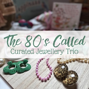 Könnte beinhalten: Ein Schmuckset bestehend aus grünen, gesprenkelten blumenförmigen Ohrringen, einer rosa Perlenkette und zwei runden Cabochons mit Leopardenmuster. Der Text "The 80's Called Curated Jewellery Trio" ist in grüner Schrift eingeblendet.