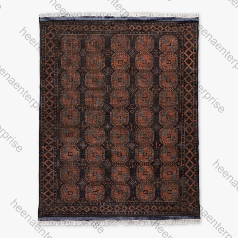 K&ouml;nnte beinhalten: Rechteckiger, gemusterter Teppich mit dunklem Hintergrund und sich wiederholenden geometrischen Formen in Rost- und Blaut&ouml;nen. Der Teppich hat einen detaillierten Rand und Fransen, die ein traditionelles Design zeigen.