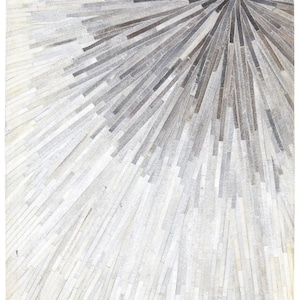 May include: A rectangular rug with a sunburst design. The rug features a pattern of radiating lines in shades of gray and white, creating a textured, eye-catching surface. The design is centered, with lines extending outwards.