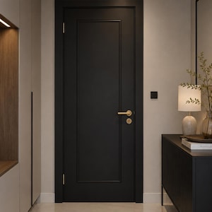 Pode incluir: Uma porta interior preta com ferragens douradas é o ponto focal desta imagem. A porta é emoldurada por uma parede de cor clara e molduras a condizer. Um armário preto com uma lâmpada e objetos decorativos está à direita.