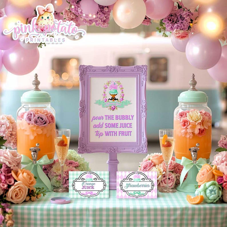 May include: A party scene with a light blue and white backdrop, featuring a table with drinks and decorations. Two glass beverage dispensers with floral arrangements flank a framed sign that reads "pour the bubbly add some juice top with fruit."
