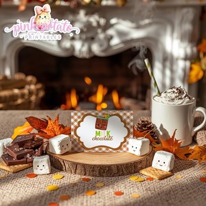 May include: A cozy autumn scene with a mug of whipped cream-topped hot chocolate, marshmallows, chocolate bars, and a card that says "Milk Chocolate." The scene is set in front of a fireplace with fall leaves and confetti.