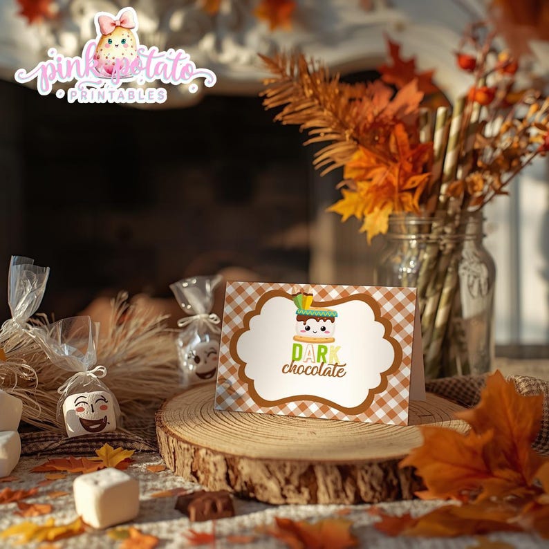 May include: A decorative card with a cartoon cake illustration and the words "Dark Chocolate" on a wooden slice. The card is set against a backdrop of fall foliage and treats.
