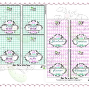 May include: Printable food tent or place cards with a pink and green theme. The cards feature labels for various fruits and juices, including orange, cranberry, mango, pineapple, strawberries, bananas, and oranges. The background has a gingham or diamond pattern.
