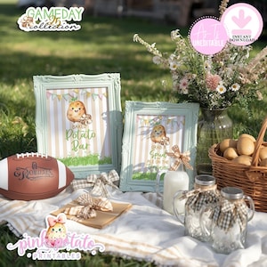 May include: A picnic setting featuring a football, framed signs, and decorative jars. The signs display the text "Baked Potato Bar" and "Grab a Spud Pile on the Toppings". A basket of potatoes and a vase of flowers are also visible.