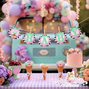 May include: A festive baby shower scene with a light blue vintage van backdrop. A banner spells "BABY" with floral and black and white patterned circles. Pink cake, ice cream cones, and balloons complete the party decor.