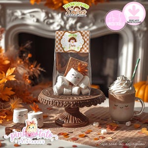 May include: Thanksgiving s'mores kit in a clear bag with a decorative label. The bag contains marshmallows, graham crackers, and a fall leaf. A mug of hot chocolate with whipped cream and a green straw is next to the bag. The words "Thanksgiving S'mores Collection" are at the top.