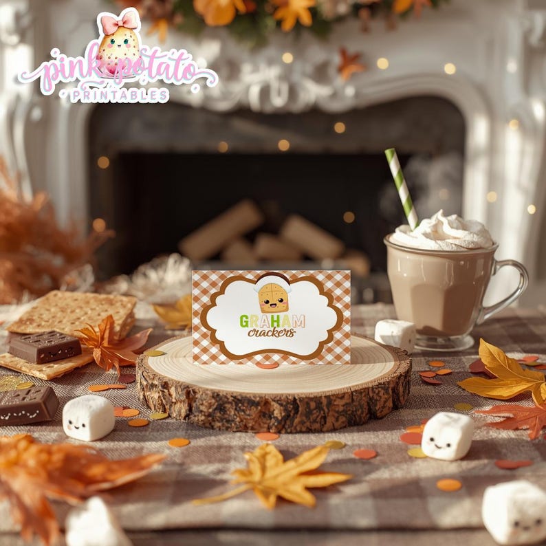 May include: A cozy autumn scene with a mug of hot chocolate topped with whipped cream, a decorative card that says "Graham Crackers", marshmallows, and fall leaves. The card is on a wooden slice.