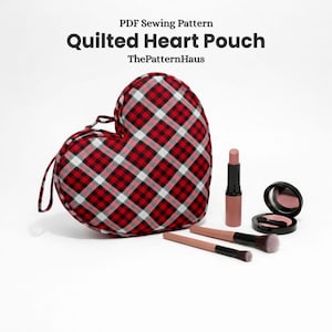 Puede incluir: Una bolsa acolchada en forma de corazón a cuadros rojos, negros y blancos, con un asa de bucle. La imagen también muestra un lápiz labial, rubor y brochas de maquillaje. El texto de la imagen dice "PDF Sewing Pattern Quilted Heart Pouch ThePatternHaus."