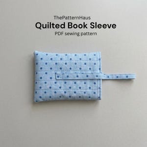 May include: A light blue quilted book sleeve with a polka dot pattern and a strap closure. The text "ThePatternHaus" and "Quilted Book Sleeve" are displayed in black, along with "PDF sewing pattern".
