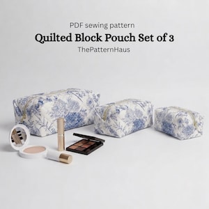 Puede incluir: Conjunto de tres neceseres acolchados con un estampado floral azul. Los neceseres, de diferentes tamaños, tienen cremalleras doradas. Se muestran artículos de maquillaje, incluyendo una polvera, un labial y una paleta de sombras de ojos, delante. El texto en la imagen dice "Quilted Block Pouch Set of 3".