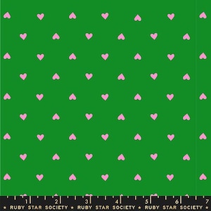 May include: Green fabric with a repeating pattern of small, pink hearts. The fabric has a ruler along the bottom edge with the text "RUBY STAR SOCIETY".