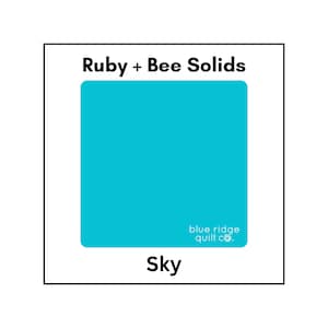 May include: A solid color fabric swatch in a bright turquoise blue. The fabric is labeled "Sky" and is part of the Ruby + Bee Solids collection from Blue Ridge Quilt Co.