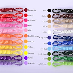 May include: A collection of colorful cords in various shades, including burgundy, cherry, and black. Each cord has a loop at the end and is paired with a color swatch and a corresponding name. The image showcases a range of colors for crafting or accessories.