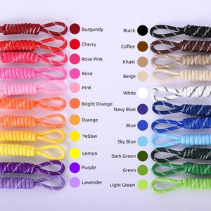 May include: A collection of colorful cords in various shades, including burgundy, cherry, and black. Each cord is looped at the end and labeled with its corresponding color name. The image showcases a range of hues, from bright orange to light green.