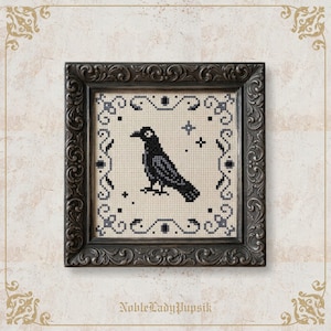 May include: A cross-stitch embroidery featuring a black crow centered on a cream-colored fabric, surrounded by a decorative border of black and gray geometric patterns and small stars, all encased in a dark, ornate, carved wooden frame.