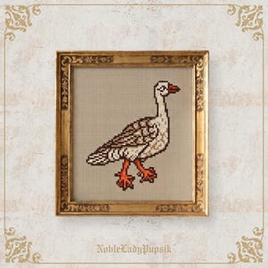 May include: A cross-stitch embroidery of a goose with white, brown, and tan feathers and bright orange feet and beak. The artwork is displayed in a rectangular, ornate, antique-style gold frame with floral carvings along the edges.