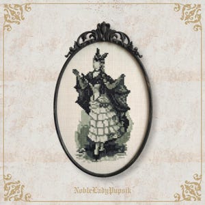 May include: A cross-stitch embroidery featuring a figure in a dark, flowing garment with a checkered skirt, displayed in an oval black frame with ornate detailing. The text NobleLadyPupsik is printed in a serif font at the bottom of the image.