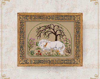 May include: Cross-stitch art of a white unicorn resting under a tree, surrounded by flowers. The framed piece has a gold ornate frame. The artwork is on a beige background. The text "NobleLadyPupsik" is at the bottom.