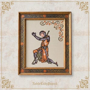 Könnte beinhalten: Ein gerahmtes Kreuzstich-Stickbild, das einen mittelalterlichen Ritter in orangefarbener und grauer Rüstung zeigt, der auf einem hellen Stoffhintergrund kniet. Der Ritter trägt eine Tunika mit einem weißen Kreuzemblem. Der Rahmen ist aus dunklem Holz.