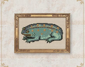 May include: Cross-stitch art of a frog in a gold frame. The frog is teal with orange spots and a dark blue back. The frame has ornate detailing. The text "NobleLadyPupsik" is at the bottom.