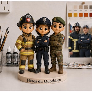 May include: A custom figurine set featuring three characters: a firefighter in tan gear, a police officer in a dark blue uniform, and a soldier in camouflage, all standing on a circular base with the text "H&eacute;ros du Quotidien" printed on the front.