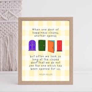 May include: A framed print with a light wood grain frame. The print features a yellow and white checkered background with four colorful door illustrations and a quote by Helen Keller.