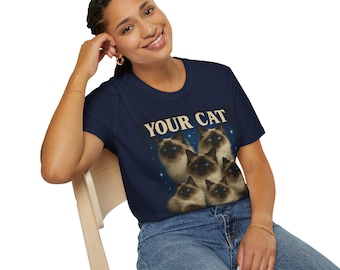 May include: Navy blue t-shirt featuring a graphic of several Siamese cats with the text "YOUR CAT" in a vintage style. The cats have blue eyes and tan fur. The shirt is a crew neck.