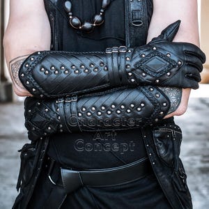 Puede incluir: Guantes de cuero negro con detalles de tachuelas y trenzados en forma de diamante. Los guantes tienen múltiples correas con hebillas y forman parte de un conjunto gótico o steampunk. El texto "Character Art Concept" es visible.