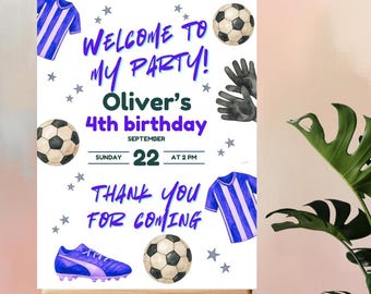 May include: A soccer-themed birthday party sign on an easel. The sign features soccer balls, jerseys, and cleats, with text that reads "Welcome to My Party! Oliver's 4th birthday" and "Thank You for Coming."